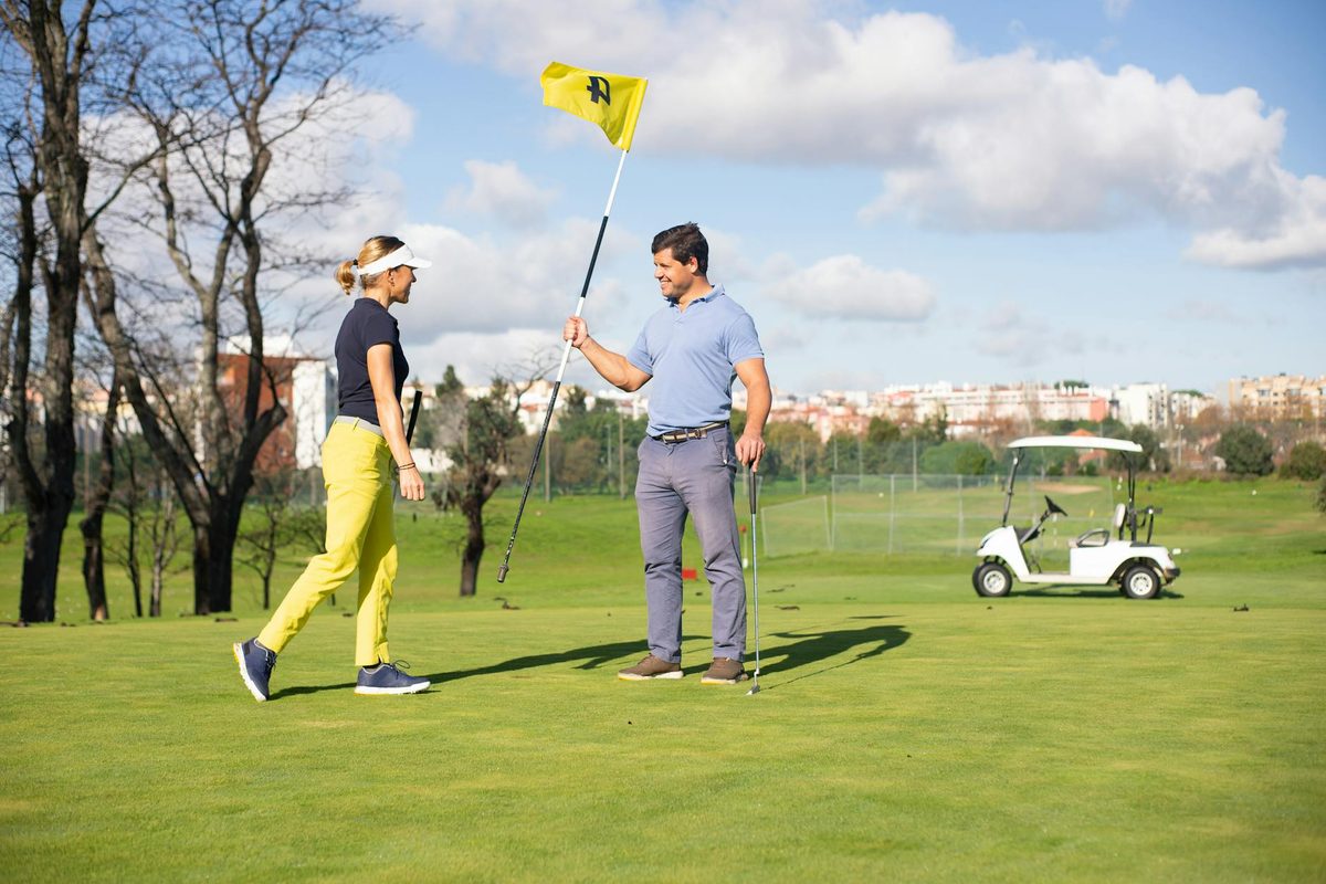 A group of golfers walking down a tree-lined fairway with bags over their shoulders