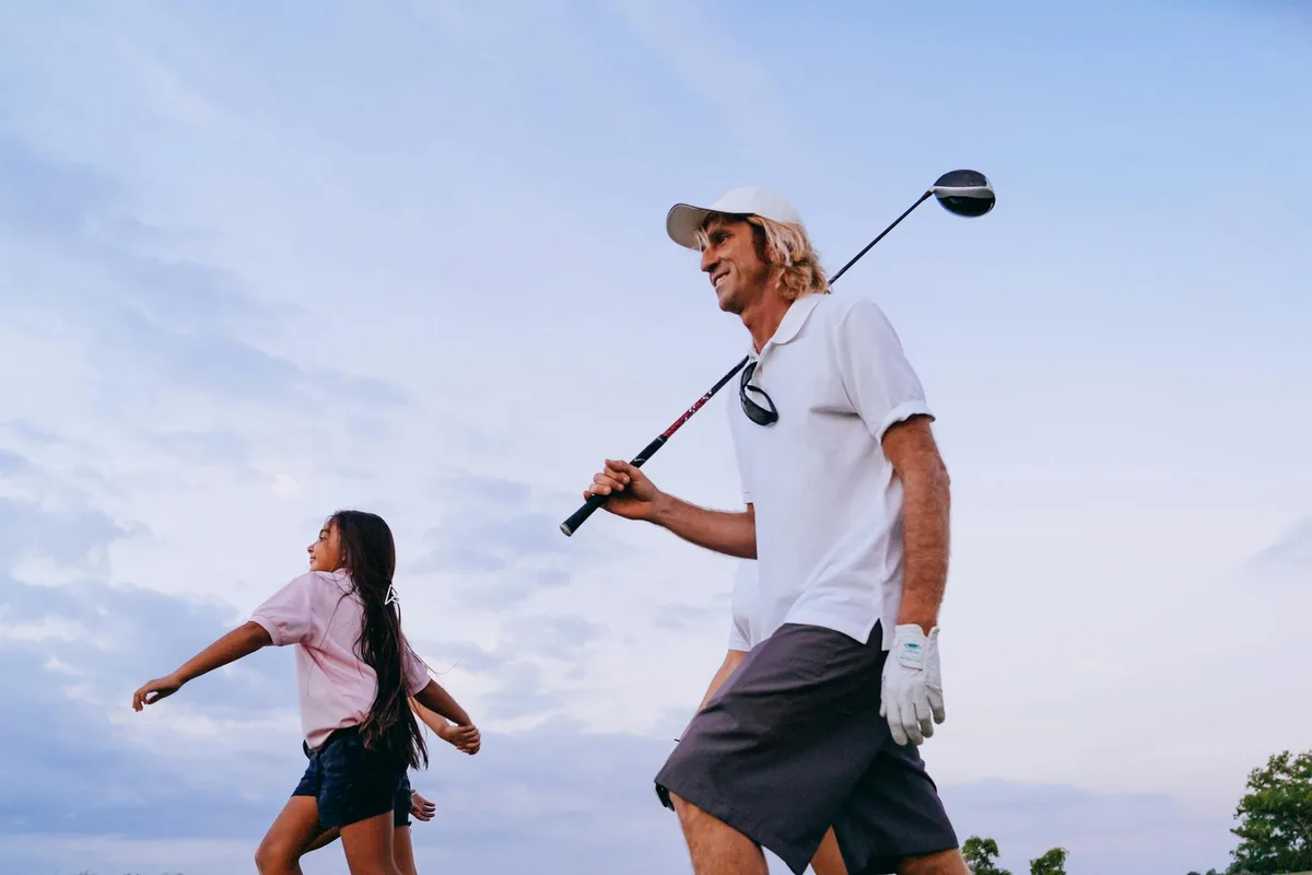 A smiling golfer on a sunny course holding a golf gift, celebrating Father's Day