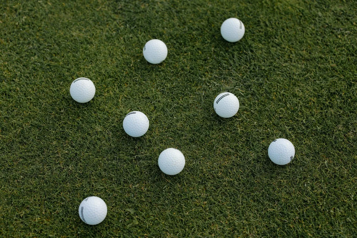A golfer mid-iron swing on a practice fairway working on ball contact