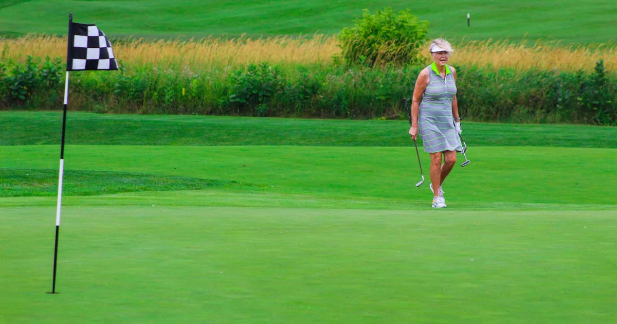 A female golfer smiling and holding her club after a great shot on a sunny UK golf course