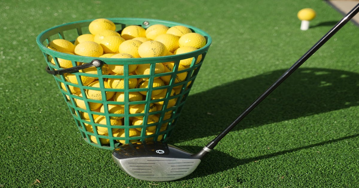 A golfer checking their phone on a sunny golf course with a bag of clubs nearby