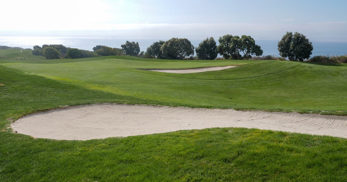 Golf course with sand trap and ocean view under a clear blue sky