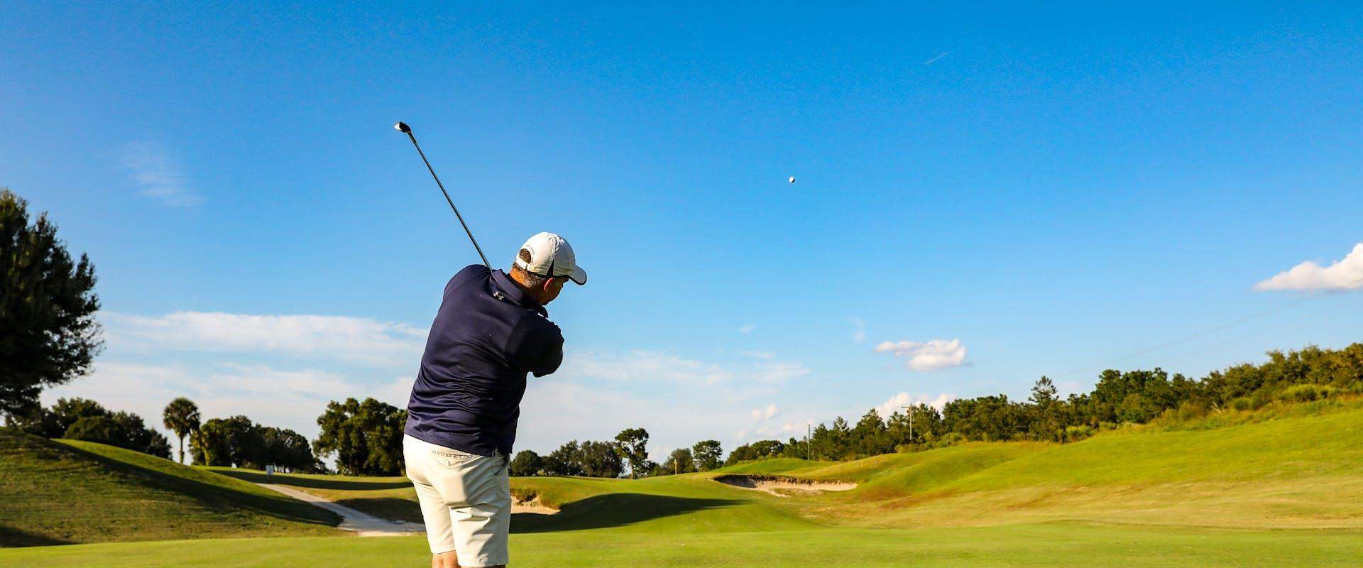Golfer practising a swing on a lush UK golf course with rolling green fairways