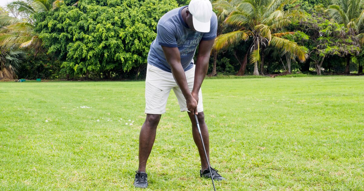 A golfer at address on the fairway preparing a short-game shot
