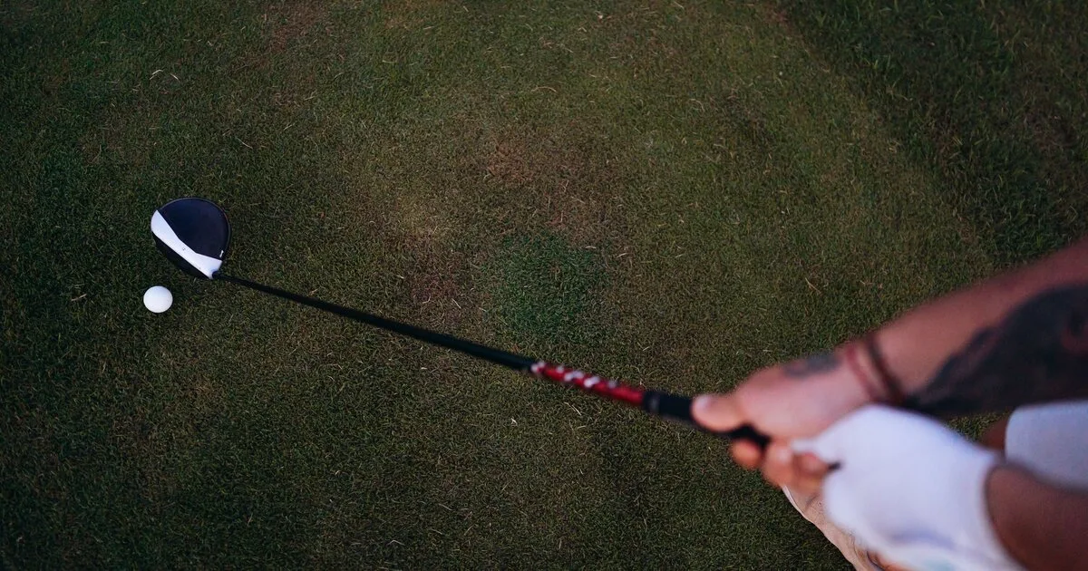 Overhead view of a golfer's hands on the grip with the clubhead behind the ball at address
