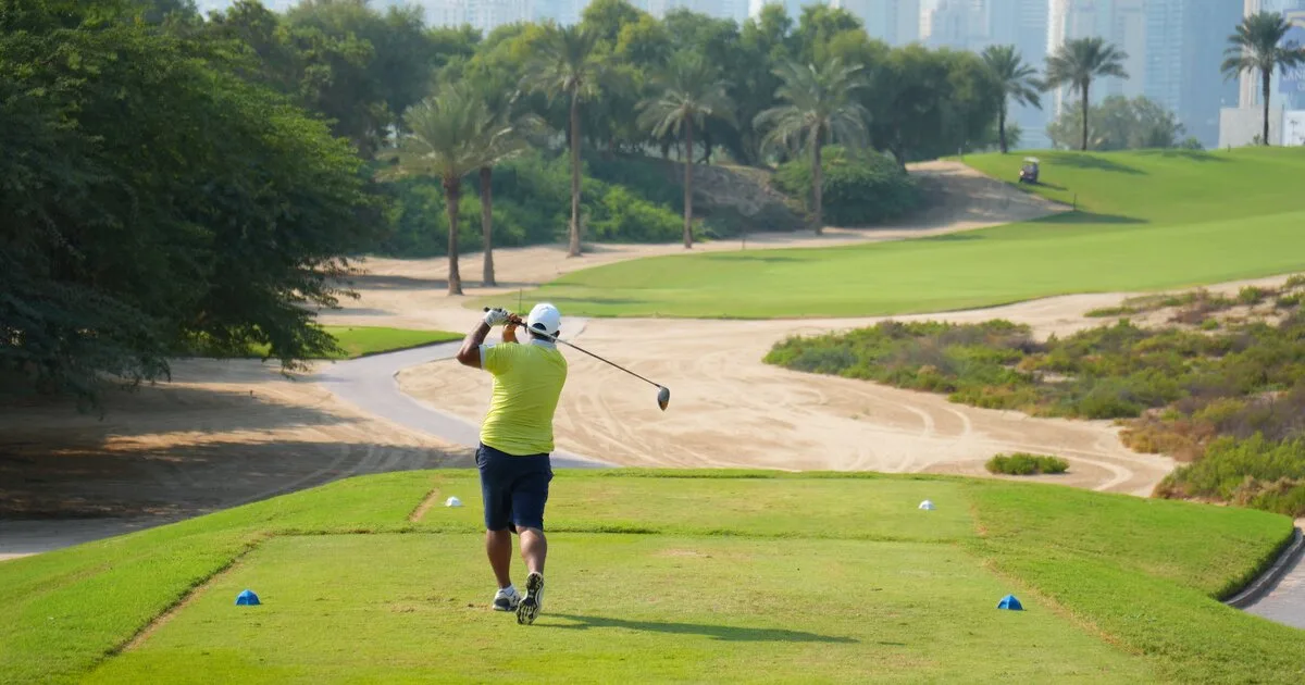 A golfer completing a driver swing with the fairway laid out ahead