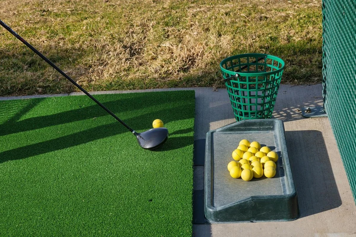 A golfer executing a pitch shot onto a green, club at follow-through with ball in the air